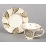 A Rockingham primrose leaf moulded breakfast cup and saucer with rustic crossed-twig handles.