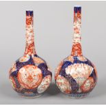 A pair of Japanese Meiji period bottle vases. With lobed globular bodies and painted with panels