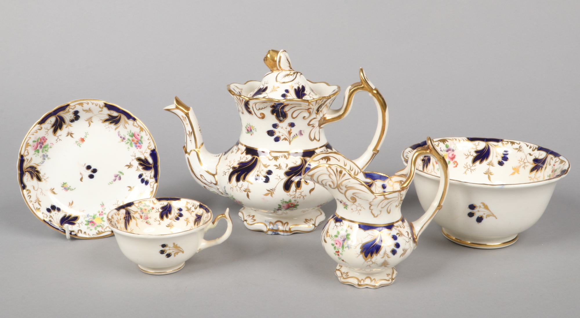 A Rockingham part tea service with single spur handles. Moulded with scrolling foliage, having wet