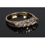 An 18 carat gold five stone diamond ring chased with scrollwork shoulders. Set with graduated Old