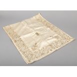 A 19th century ivory silk table covering embroidered with gold thread with a border of trailing