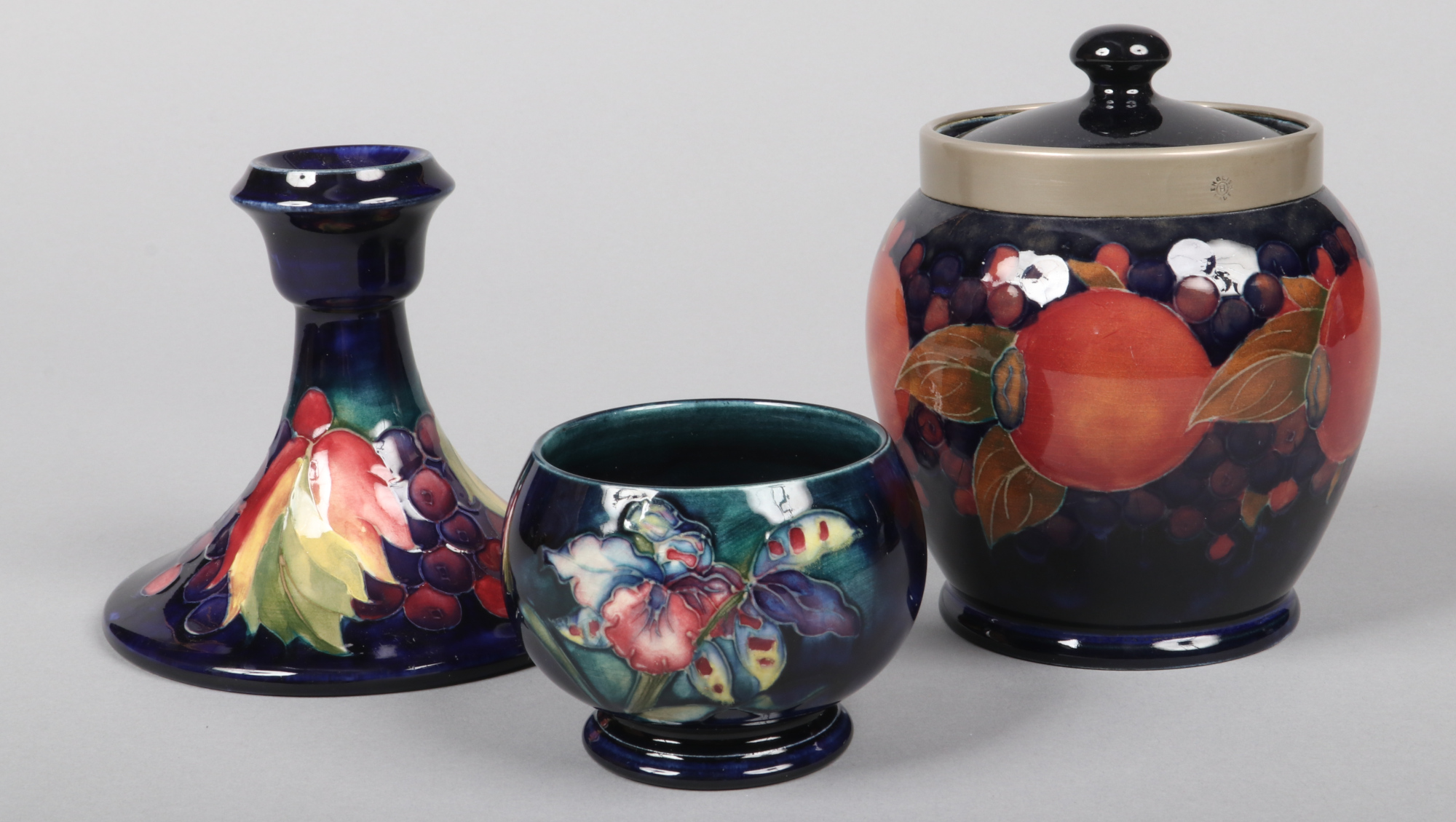 Three pieces of Moorcroft pottery. A biscuit jar and cover with pewter mount and decorated in the