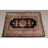 A black ground wool rug. With wide stylized border and central medallion, 128cm x 172cm.