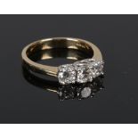 An 18 carat gold three stone diamond ring. Claw set with three graduated brilliant cut diamonds.