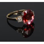 An 18 carat gold Art Deco style cocktail ring. Set with a large ovoid pink gemstone flanked by a