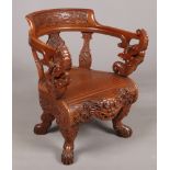 A 20th century Chinese hardwood armchair. Profusely carved with turtles, cloud scrolls, dogs of fo