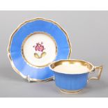 A Rockingham teacup and saucer with square handle, gilded, having blue grounds and painted with