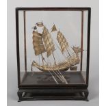 A cased Chinese export silver model of a seven gun war junk. Raised on a carved hardwood wave scroll