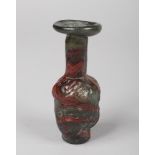 A Romanesque glass bottle vase. With green and red swirl ground and the main body formed as the head