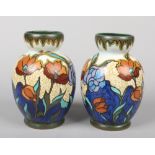 A pair of Gouda pottery mantel vases decorated with stylized poppies. Painted marks, 22.5cm. Hair