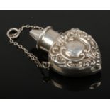 An Edwardian silver scent bottle by William J Holmes. Heart formed, embossed with scrolls and having