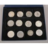 Twelve white metal coins / medals. Including Chinese examples, South Afica and New Zealand Shillings