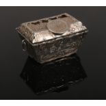A Continental silver casket of sarcophagus form with coin thumb piece. Embossed with pastoral scenes