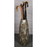 A large ceramic vase with a collection of wooden/metal walking sticks/umbrella