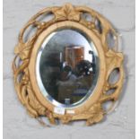 A wooden oval carved mirror (46.5cm x 40cm) Bottom of wood frame needs re gluing.