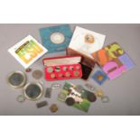 A box of collectables including coin sets, Rolls Royce badge and a pair of silver plated