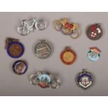 Nine vintage cycling badges and medals including enameled examples.