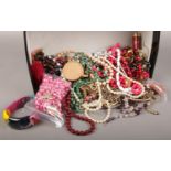 A shoebox containing a large collection of costume jewellery and beads etc.