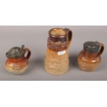 Three c19th salt glazed stoneware jugs with sprig mould decoration to include silver lidded