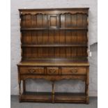 A Titchmarsh & Goodwin oak dresser. With delft rack having panelled back incorporating a cupboard