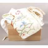A box of mixed linens, table cloths, doilies, cushion covers with tapestry detailing etc