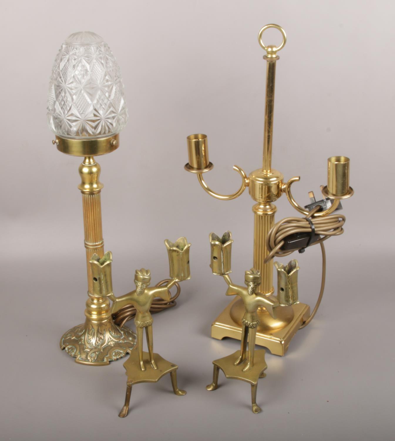 A pair of figural brass candlesticks along with two brass tables lamps to include cut glass shade