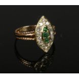 An 18ct gold emerald and diamond cluster ring set on a navette shaped panel. 3 grams gross weight,