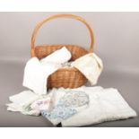 A wicker basket to include linen table clothes, doilies, linen napins