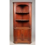 A Georgian mahogany floor standing corner cupboard. With open arch top section over panelled