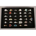 Thirty five dress rings in a display box, including white and coloured paste set examples.