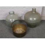 Two glass carboy bottles along with a brass jam pan.