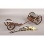A wood and metal model of an artillery cannon and cart, along with a decorative revolver.