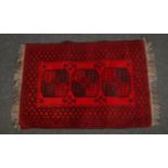 A red ground wool rug with geometric design. (144cm x 100cm).