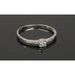 A 9ct white gold and diamond ring. Set with an elevated principle stone and four diamonds to each