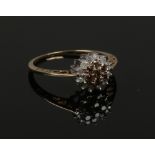A 9ct gold two tone diamond cluster ring on open scrollwork shank. Size T. One of the clear stones