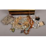 A tin of vintage costume jewellery including an amber necklace.