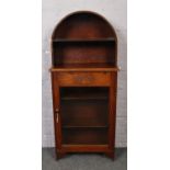 A small oak bookcase, with glazed cupboard base and open dome top.