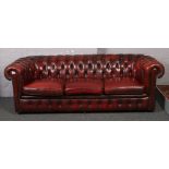 An ox blood deep buttoned leather three seat Chesterfield settee. Generally good. Stain to