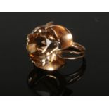 A 14ct rose gold cocktail ring. With a large coloured paste stone in a floriform setting. Stamped .