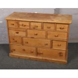 A haberdashery style pine bank of thirteen graduated drawers, 119cm wide, 83cm high, 47cm deep.