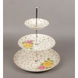 A 1940s pottery three tier cake stand with chromed handle.