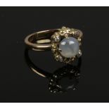 A yellow metal, star sapphire and diamond ring. Set with a central cabochon on a scrolling shank