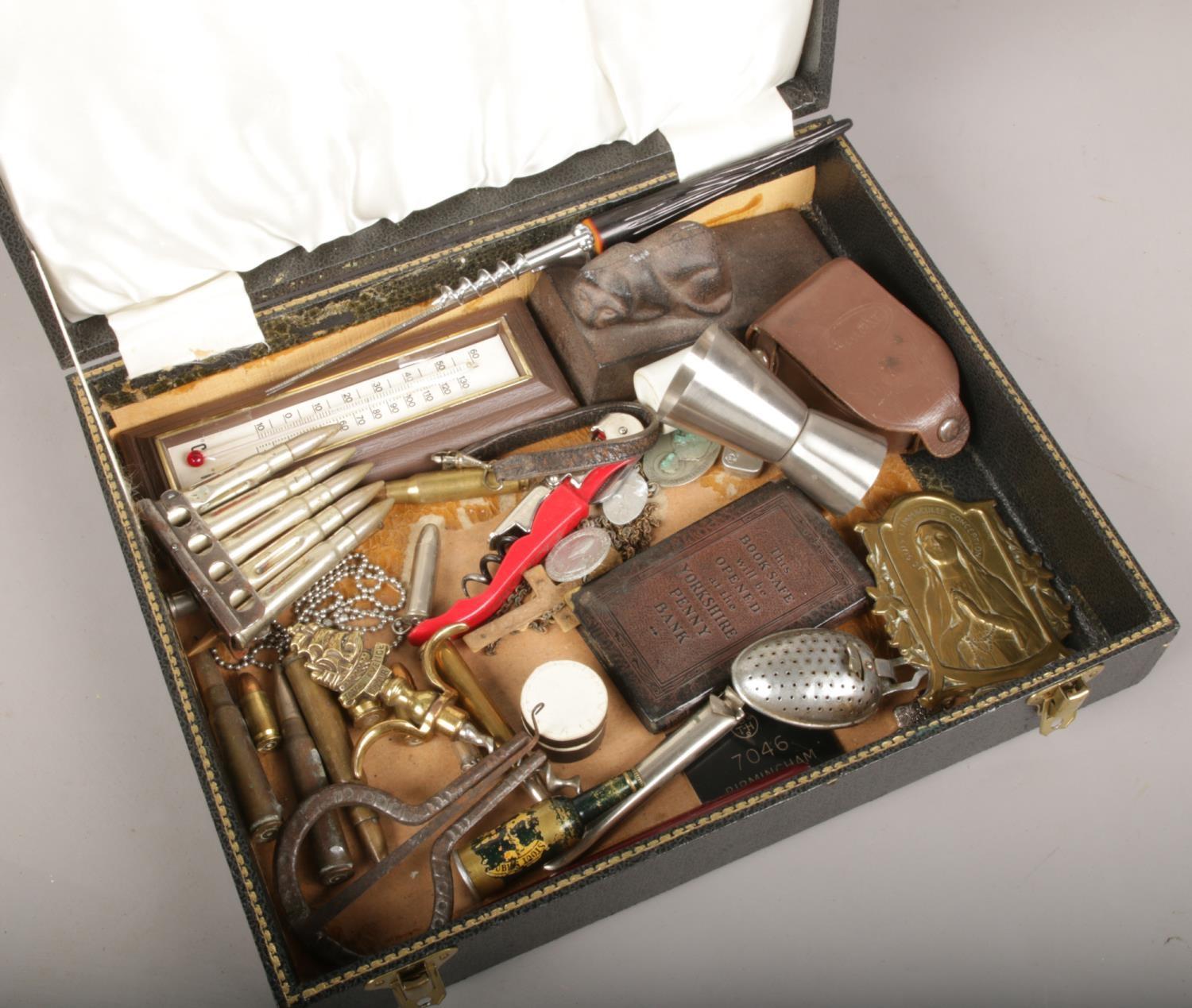 A case of collectables, to include Yorkshire Penny Bank book safe, bullets, religious items etc.