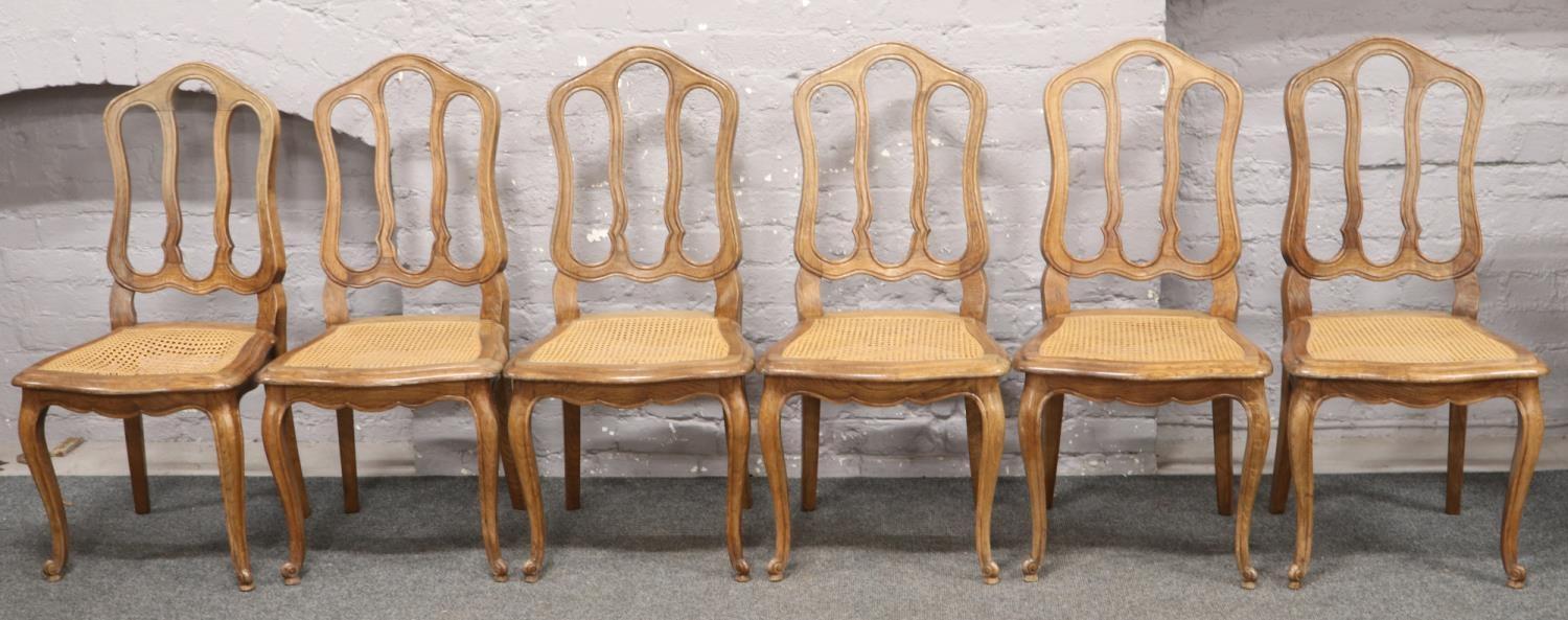 A set of six Continental carved oak canework dining chairs, raised on cabriole legs. (Damage to