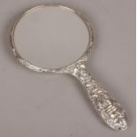 A silver mounted hand mirror with repousse decoration, assayed Birmingham 1987 by W I Broadway & Co.