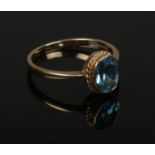 A 9ct gold blue topaz dress ring with ropetwist border. Size N.