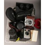 A tray of cameras, photographic equipment and pair of cased Super Zenith binoculars. Including