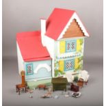 A painted wooden doll's house with a small collection of doll's house furniture.