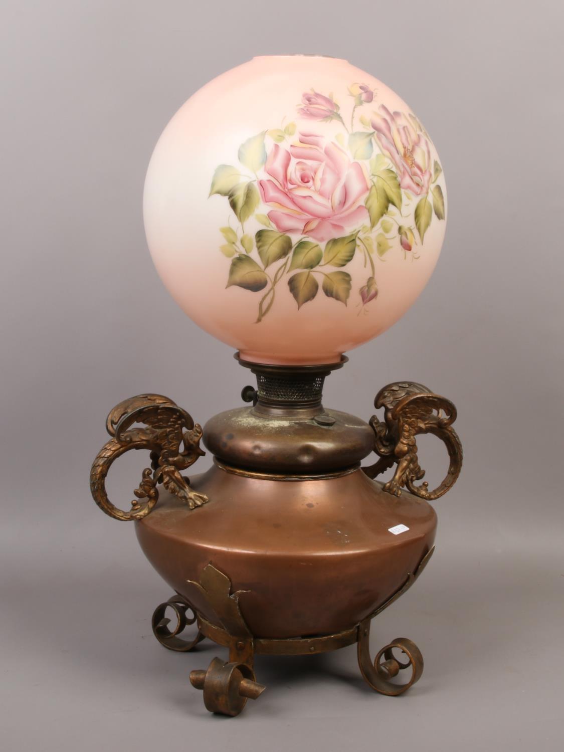 A large Victorian copper oil lamp. With wrought supports and eagle handles. With later glass shade