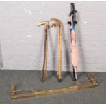 A collection of walking sticks, wooden & metal examples to include a brass fire fender